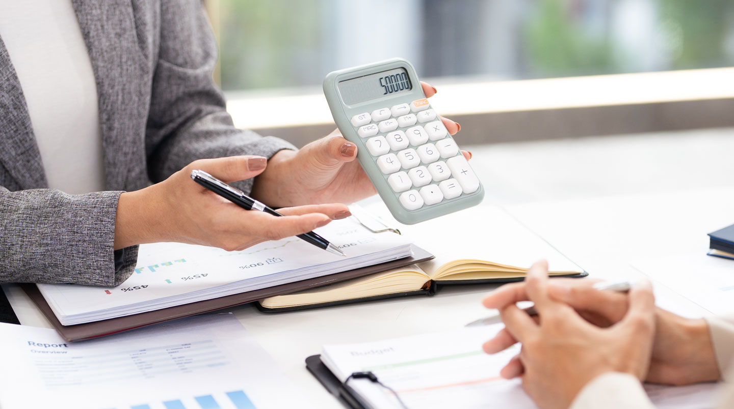Gros plan sur écran d'ordinateur portable affichant l'interface d'un simulateur de prêt immobilier en français, mains d'une personne en train de saisir des données de calcul de mensualités sur un bureau contemporain